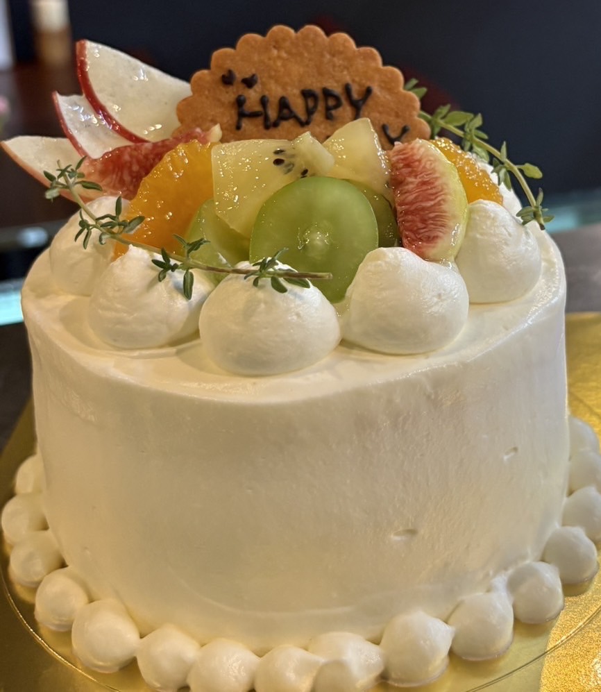 色とりどりの果物とクッキーを飾ったホールケーキ
